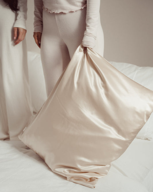 Luxe 100% moerbei zijden kussensloop van Silky Family in de kleur creme wordt vastgehouden door model